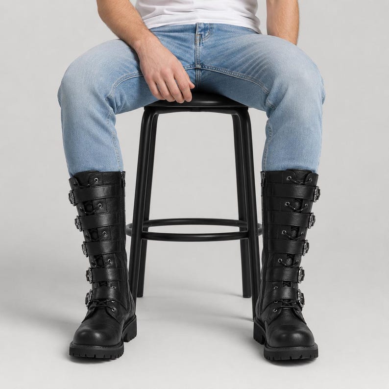 May include: A pair of black mid-calf boots featuring a lace-up front design with five horizontal straps across the shaft. Each strap is secured with a silver-toned metal buckle. The boots have a rounded toe, a thick lug sole, and a side zipper closure.