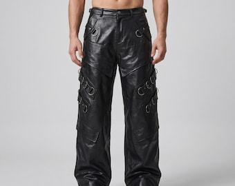 Op de afbeelding: Zwarte leren broek met meerdere zilveren metalen ringen en decoratieve stiksels. De broek heeft een wijde pijp en een klassieke vijf-zakken stijl. De broek is gemaakt van duurzaam leer.