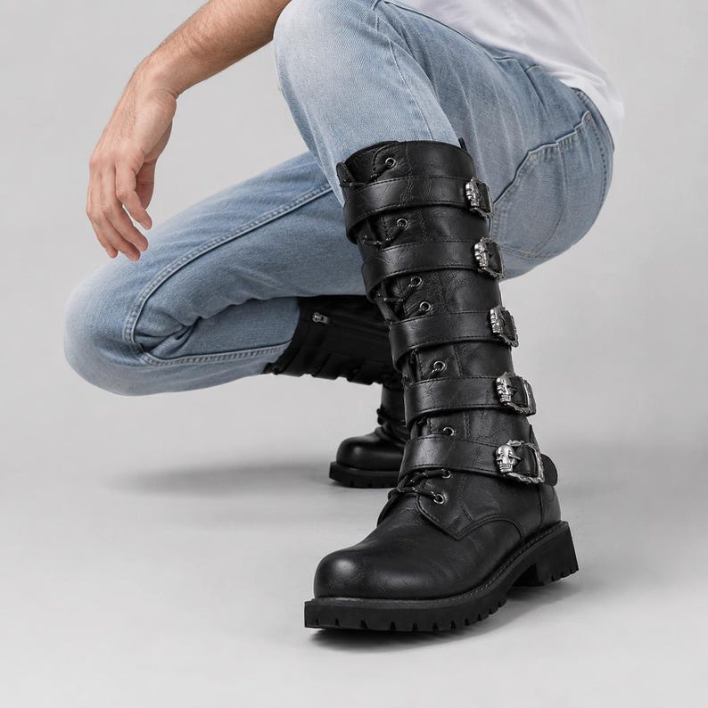 May include: A pair of black mid-calf boots featuring a lace-up front and five horizontal straps with silver-toned skull-shaped buckles. The boots have a rounded toe, a thick lug sole, and a smooth finish, extending to the mid-calf area.