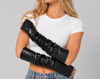 Op de afbeelding: Een paar zwarte vingerloze handschoenen van operalengte, gemaakt van een glad, mat materiaal. De handschoenen reiken tot voorbij de ellebogen en hebben een geplooid, gerimpeld ontwerp over de gehele lengte van de armen, met open vingertoppen.