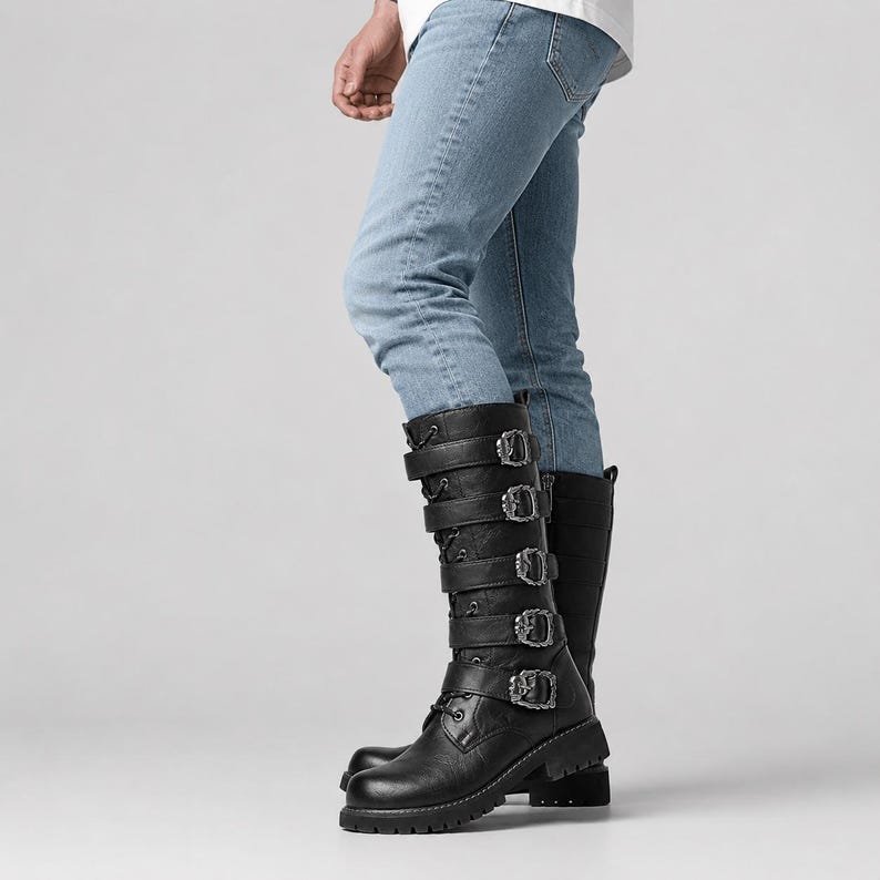 May include: Black mid-calf boots featuring five horizontal straps with ornate silver-toned metal buckles and a lace-up front closure. The boots have a rounded toe, a low block heel, and a textured finish, paired with light blue denim jeans.