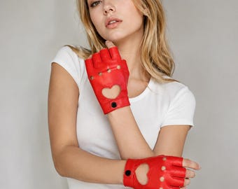 Op de afbeelding: Een paar vingerloze handschoenen van felrood leer met een hartvormige uitsparing op de rug van de hand, kleine ronde ventilatiegaatjes over de knokkels en een enkele zwarte drukknoopsluiting bij de pols voor een goede pasvorm.