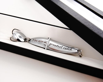 May include: A silver fishing lure in a black box with a clear lid. The lure has the words "You are my greatest catch" engraved on it.
