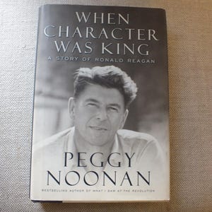Puede incluir: Un libro titulado "When Character Was King: A Story of Ronald Reagan" de Peggy Noonan. La portada presenta un retrato en blanco y negro de Ronald Reagan. El nombre de la autora est&aacute; en negrita.