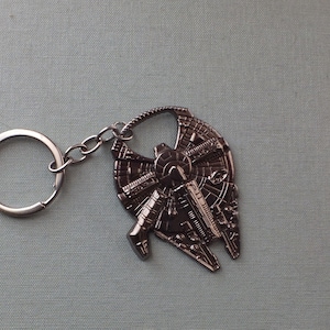 Peut inclure: Un porte-clés en métal argenté représentant un modèle détaillé du Faucon Millenium, le vaisseau spatial de Star Wars. Le porte-clés est doté d'un anneau argenté pour l'attacher aux clés.