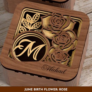 May include: Wooden box with a laser-cut design featuring roses and leaves. The box has a gold-colored interior and a circular monogram with the letter "M". The name "Michael" is engraved on the box. The text "JUNE BIRTH FLOWER: ROSE" is at the bottom.