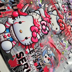 Puede incluir: Una lámina de pegatinas transparente con personajes de dibujos animados de temática de terror. El diseño incluye un personaje de Hello Kitty con disfraz de payaso, salpicaduras de sangre y el texto "Serial Killer". También se ven otros personajes.