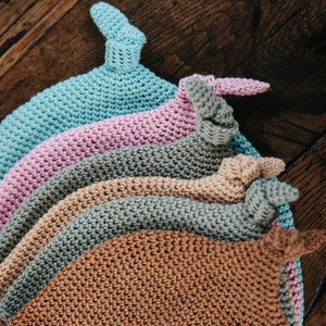 Peut inclure: Cinq bonnets en crochet de différentes couleurs, empilés les uns sur les autres. Les bonnets sont dans des tons de bleu, rose, vert, beige et marron.