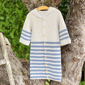 May include: A crocheted hooded cardigan with long sleeves and a striped pattern in blue and white. The cardigan has wooden buttons down the front.
