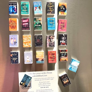 May include: A collection of miniature book magnets with colorful covers, including titles like "Binding," "A Court of Mist and Fury," and "Archer's Voice." A small card reads "Thanks for your order from bookishBlueLine."