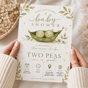May include: A rectangular baby shower invitation card featuring a watercolour illustration of two smiling peas in a green pod. The text reads: Please join us for a baby shower, honouring the mum-to-be, two peas in a pod, with event details included.