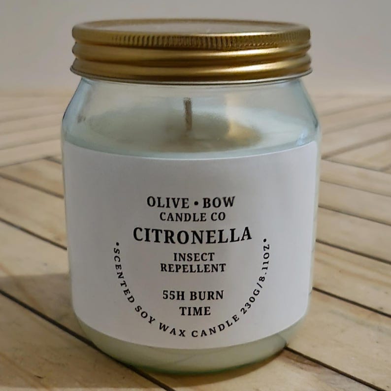 Peut inclure: Une bougie en pot de verre transparent avec un couvercle dor&eacute;. L'&eacute;tiquette indique "Olive Bow Candle Co Citronella Insect Repellent" avec une dur&eacute;e de combustion de 55 heures. La bougie contient 230g de cire de soja parfum&eacute;e.