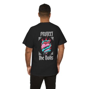 Puede incluir: Camiseta negra con un estampado gr&aacute;fico de un coraz&oacute;n envuelto en una serpiente con llamas y el texto "Protect the Dolls".