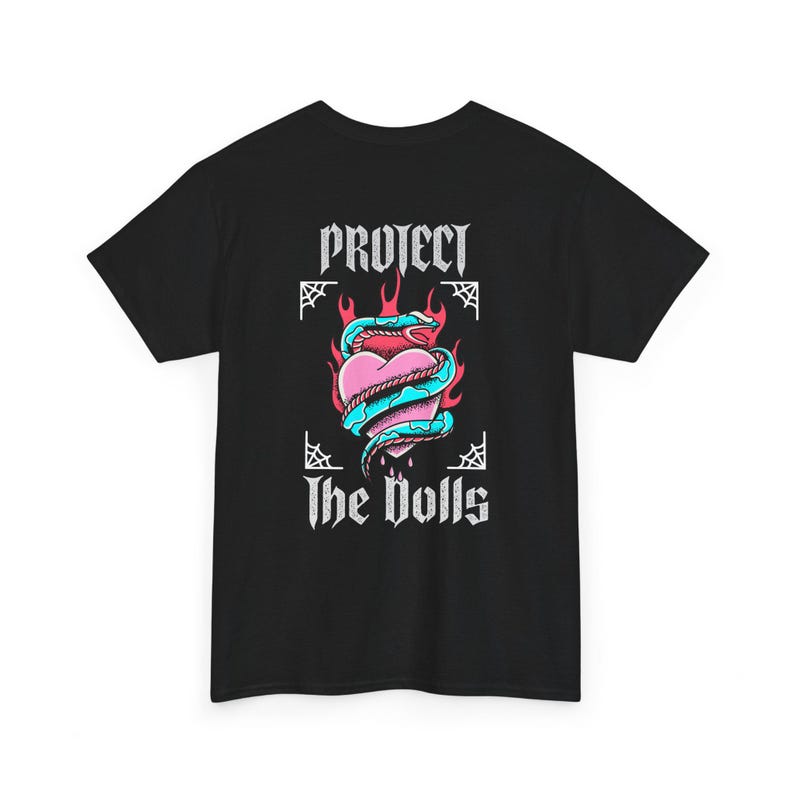 Puede incluir: Camiseta negra con un estampado gr&aacute;fico de un coraz&oacute;n envuelto en una serpiente con llamas y el texto "Protect the Dolls" en una fuente g&oacute;tica.