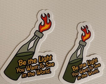 May include: Two green and yellow stickers with a cartoon image of a lit Molotov cocktail. The text on the stickers reads "Be the Light You Want To See in the World."