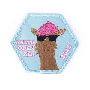 May include: A light blue hexagonal patch with a white outline. The patch features a cartoon llama wearing sunglasses and a pink mohawk. The text "ALTO OPEN AIR 2018" is embroidered in pink and white.