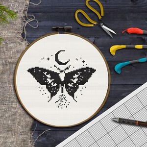 Pu&ograve; includere: Telaio da ricamo a punto croce con un disegno di farfalla in bianco e nero, una luna crescente e stelle. Include filo da ricamo, forbici e carta quadrettata con una penna. Il telaio ha un diametro di circa 20 cm.
