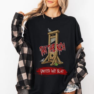 May include: Black t-shirt featuring a guillotine graphic with the text "TAX THE RICH" in red, and "UNITED WE SLAY" in white. The design includes pigeons and a small pile of money. The shirt has short sleeves.