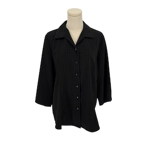 May include: A black button-down shirt with a subtle dotted pattern. The shirt has a classic collar and three-quarter sleeves. The garment is displayed on a mannequin against a white background.