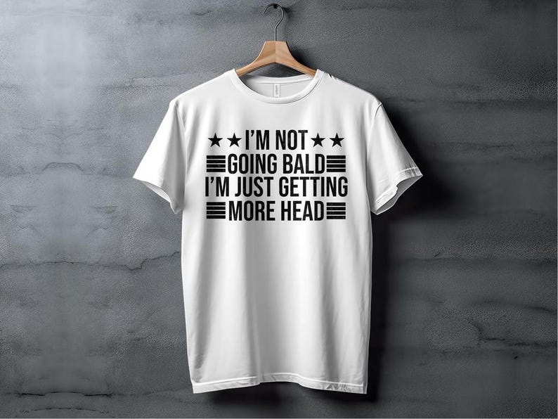 May include: White t-shirt with black text that reads "I'm not going bald I'm just getting more head" with three stars on each side of the text.