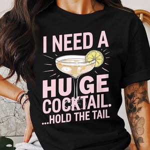 May include: Black t-shirt with a pink graphic that says "I need a huge cocktail...hold the tail". The graphic also includes a yellow lemon and a cocktail glass.