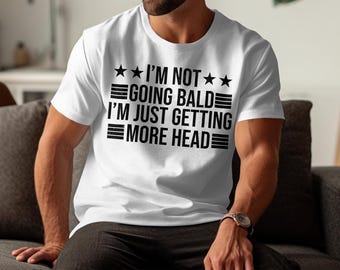 May include: White t-shirt with black text that reads "I'm not going bald I'm just getting more head" with three stars on each side of the text.