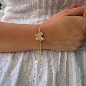 May include: Gold-toned butterfly bracelet with a small turquoise accent. The butterfly charm is the focal point, attached to a delicate chain. The bracelet is worn on a wrist, showcasing the jewelry's design and craftsmanship. The bracelet has a small charm at the end of the chain.