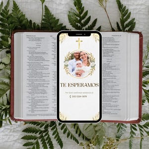 May include: A smartphone displays a family photo with a gold cross and floral design. The text "TE ESPERAMOS" is visible, along with a phone number. The phone rests on an open Bible with green foliage.