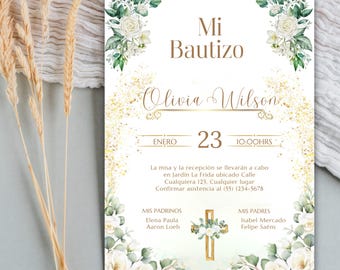 May include: A white invitation card with gold accents and floral arrangements. The text "Mi Bautizo" is at the top, with "Olivia Wilson" in elegant script. The date "23 ENERO 10:00HRS" is also displayed.