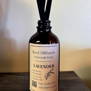Może przedstawiać: Ciemnobrązowa szklana butelka z czarnymi patyczkami, z etykietą "LAVENDER" od "Forestwalk Finds". Etykieta zawiera składniki i instrukcje odwracania patyczków dla odświeżonego zapachu. Dyfuzor patyczkowy.