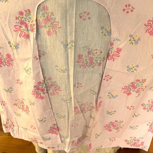 May include: A pink and blue floral fabric with a small white polka dot pattern. The fabric has a large opening in the center, creating a unique design.