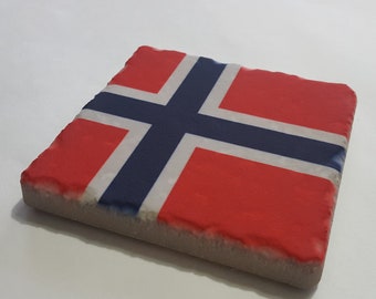 May include: A square coaster with a rough, textured surface. The coaster features a printed image of the Norwegian flag, with red, white, and blue colors.