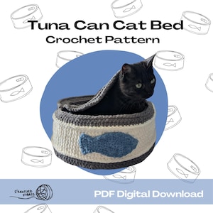 以下が含まれることがあります： 青い魚の模様がついたツナ缶の形をした、かぎ針編みの猫用ベッド。黒い猫がベッドの中で休んでいます。画像には「Tuna Can Cat Bed Crochet Pattern」と「PDF Digital Download」のテキストが表示されています。