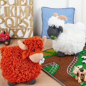 Peut inclure: Deux animaux de la ferme en peluche : une vache des Highlands rousse et un mouton blanc avec une tête grise. La vache a de grandes cornes et un nœud bleu. Le mouton a un corps blanc duveteux et des cornes beiges. Ils sont sur un tapis sur le thème de la ferme.