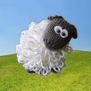 May include: A gray knitted sheep with white yarn for wool. The sheep has large black eyes and a white nose.