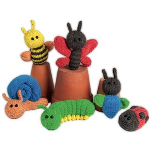 Könnte beinhalten: Eine Sammlung von sechs gestrickten Insekten- und Gartentierspielzeugen, darunter eine gelb-schwarze Biene, ein schwarzer Schmetterling mit roten Flügeln, eine blaue Schnecke, eine grüne Raupe, ein blauflügeliges Insekt und ein rot-schwarzer Marienkäfer.