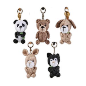 May include: Five knitted animal keychains: a panda, a teddy bear, a dog, a bunny, and a black bear. Each keychain has a metal ring and a small loop for attaching to keys or bags. The animals are in various shades of brown, black, and white.