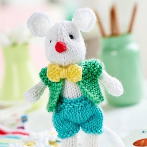 Pode incluir: Um brinquedo de rato branco de malha feito à mão, com orelhas grandes, nariz vermelho e olhos pretos. O rato usa um casaco verde, uma gravata borboleta amarela e calções azuis. Um item artesanal.