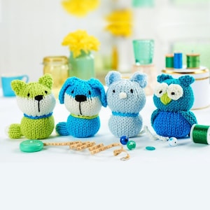 Può includere: Una collezione di quattro giocattoli di animali fatti a mano: una volpe verde, un cane blu, un orso azzurro e un gufo blu. Ogni giocattolo ha un design unico con colori e dettagli a contrasto. I giocattoli sono disposti su una superficie bianca con accessori per cucire.