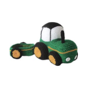 May include: A green and black crocheted tractor with a matching trailer. The tractor has yellow detailing, black wheels with yellow centres, and a white cab. The trailer has similar detailing. Two white buttons are on the front of the tractor.