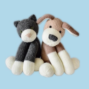 Puede incluir: Dos animales de peluche tejidos: un gato gris y un perro marrón. El gato tiene ojos verdes y una nariz rosa, mientras que el perro tiene una nariz negra y orejas caídas. Ambos tienen patas blancas y están sobre un fondo azul claro.