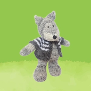 Könnte beinhalten: Ein gestricktes Wolfsspielzeug in Grau- und Weißtönen mit einer schwarzen Nase und kleinen schwarzen Augen. Der Wolf trägt eine graue Jacke mit weiß-grau gestreiften Ärmeln. Der Hintergrund ist ein grüner Farbverlauf.
