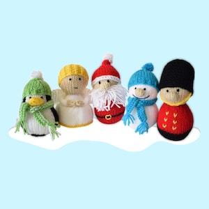 Może przedstawiać: Kolekcja pięciu dzierganych ozdób świątecznych. Ozdoby obejmują pingwina, anioła, Świętego Mikołaja, bałwana i brytyjskiego strażnika. Każda ozdoba ma na sobie czapkę i szalik.