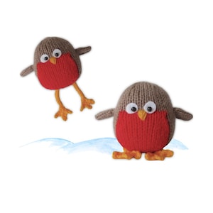Könnte beinhalten: Zwei gestrickte Rotkehlchen-Vogelornamente. Die Vögel haben braune Köpfe, rote Brüste und orangefarbene Füße. Ein Vogel steht, der andere ist im Flug. Der Hintergrund hat eine blaue Aquarellwäsche.