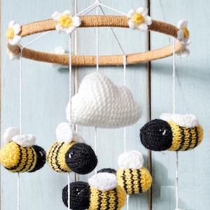 May include: A white crocheted cloud hangs from a wooden ring with crocheted daisies. Five crocheted bees with black and yellow stripes hang from the ring.