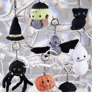 May include: A collection of handmade Halloween-themed keychains. The keychains include a black witch hat, a Frankenstein's monster, a black cat, a bat, a spider, a pumpkin, and a ghost. Each keychain is made of knitted yarn and features a metal keyring.