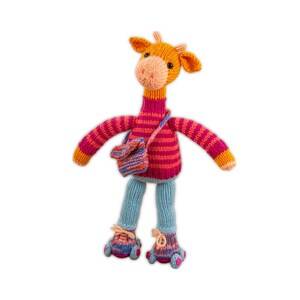 Op de afbeelding: Een handgemaakte gebreide giraffepop met oranje, roze en blauwe accenten. De giraffe draagt een gestreepte roze trui, een blauwe broek en bijpassende schoenen. Het heeft een kleine blauwe en oranje tas. Een grillig speelgoed.