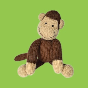 May include: A handmade knitted monkey toy in shades of brown and beige. The monkey has a smiling face with black embroidered eyes and a stitched mouth. The arms and legs are brown with beige accents on the hands and feet. The background is a solid green.