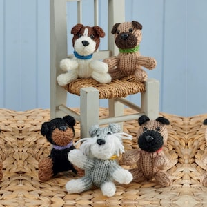 May include: A collection of handmade knitted dog toys in various breeds and colors. The dogs are sitting on a small wicker chair and a woven mat. The dogs have different colored collars.