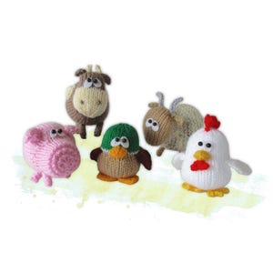 May include: Five knitted farm animal figures are displayed. The set includes a pink pig, a brown cow, a duck with a green hat, a goat, and a white chicken with a red comb. Each figure has large eyes and is made of yarn.